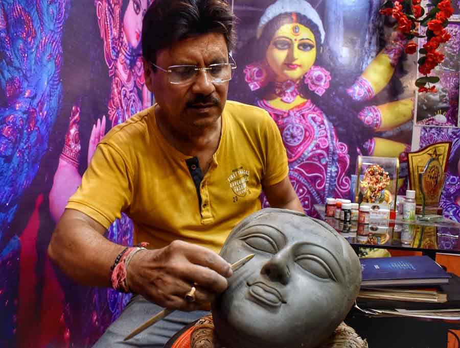 60 days ahead of Durga Puja, clay model artist Indrajit Paul adds finishing touches to a Durga idol's face at Kumartuli 