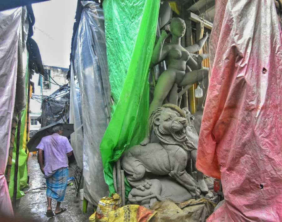 Artisans use plastic sheets to provide extra cover to unfinished Durga idols from the rain at Kumartuli on Friday