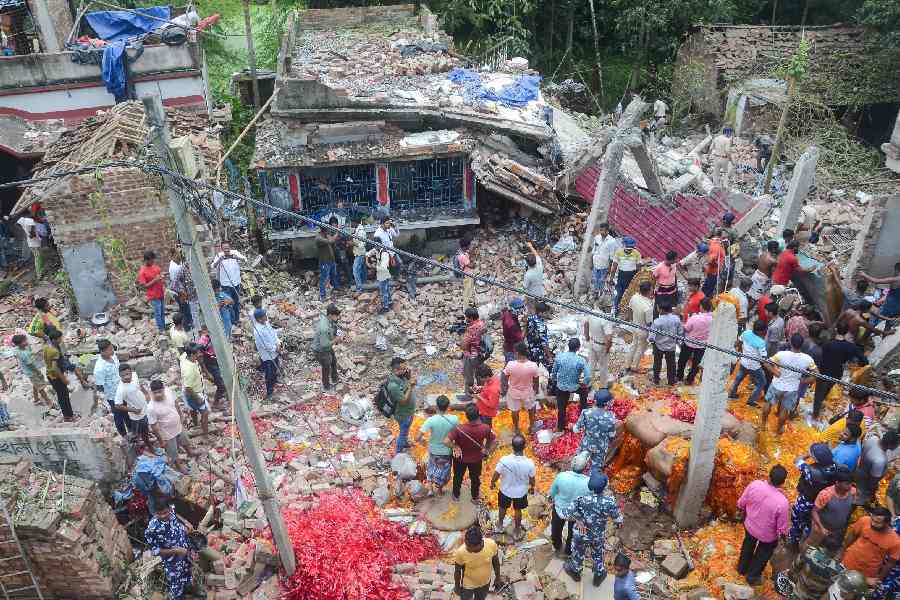 People and security personnel gather after a blast at an illegal firecracker factory in which at least four people were killed and several others injured