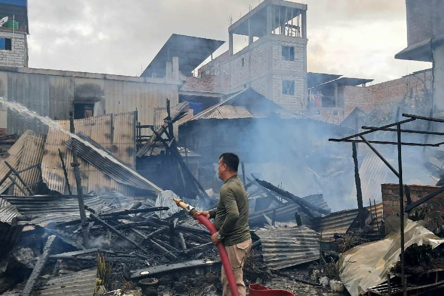 A firefighter douses flames after unidentified miscreants burnt three houses, in Imphal