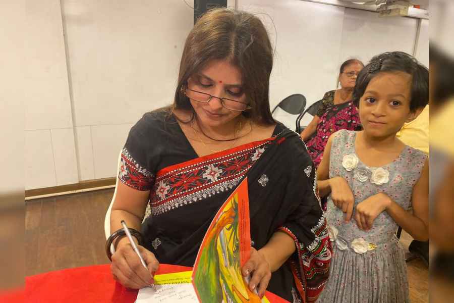 Author Ankhi Dasgupta signing a copy of her book for a young reader