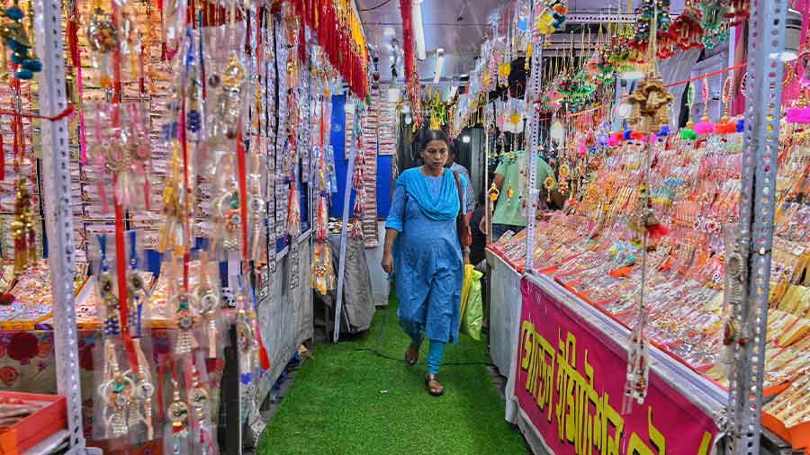 A woman glances at rakhis while walking through rows of rakhi stalls in Hatibagan