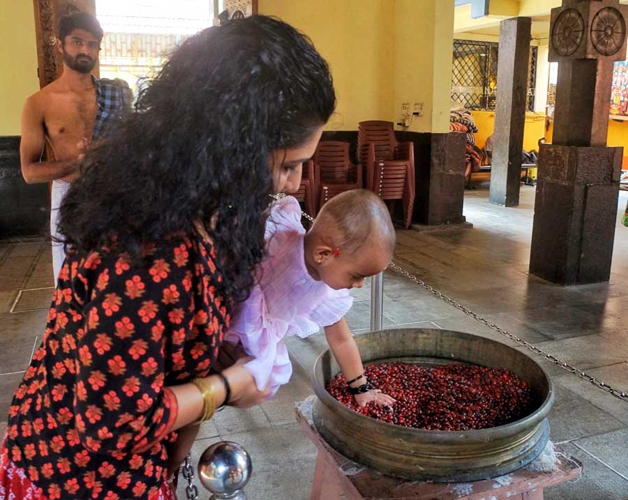 A baby in a woman’s lap plays inside the temple 