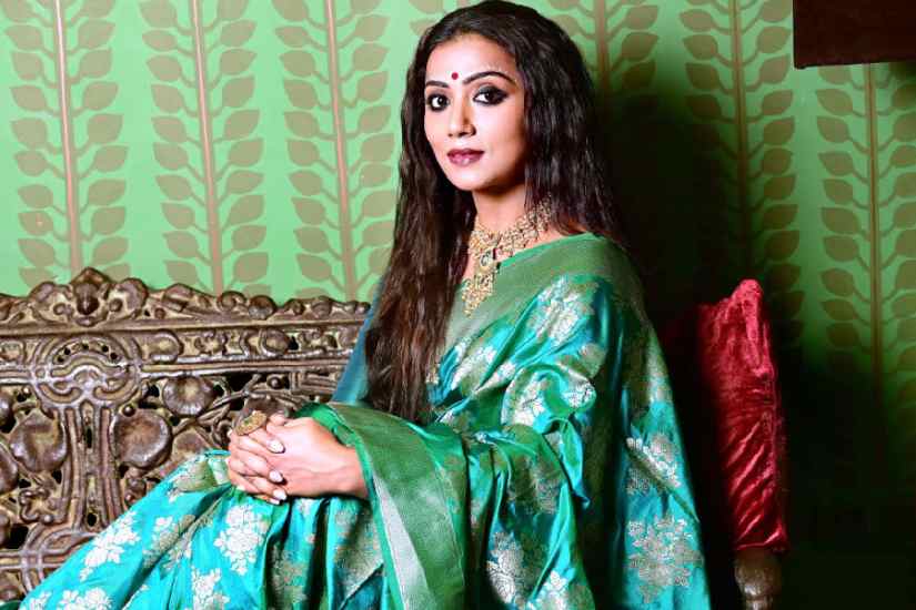 In this reception look, Anindita draped a katan silk Benarasi featuring the gulab buta in a contemporary style. The make-up was kept simple with smudged kohl eyes and a tint of maroon on the lips, completed with the hair worn open. Abhijit showed a simple chandan art style in this look by drawing it only on the forehead in a double line with dot motifs, leaving out the kalkas