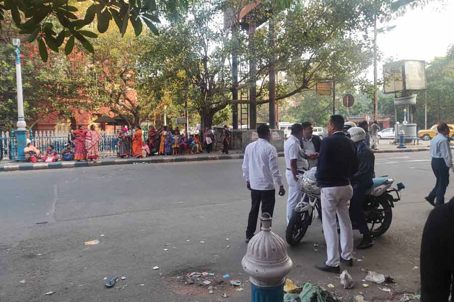 Depositors wait on the other side of the road after being chased away by police post designated deposit hours.