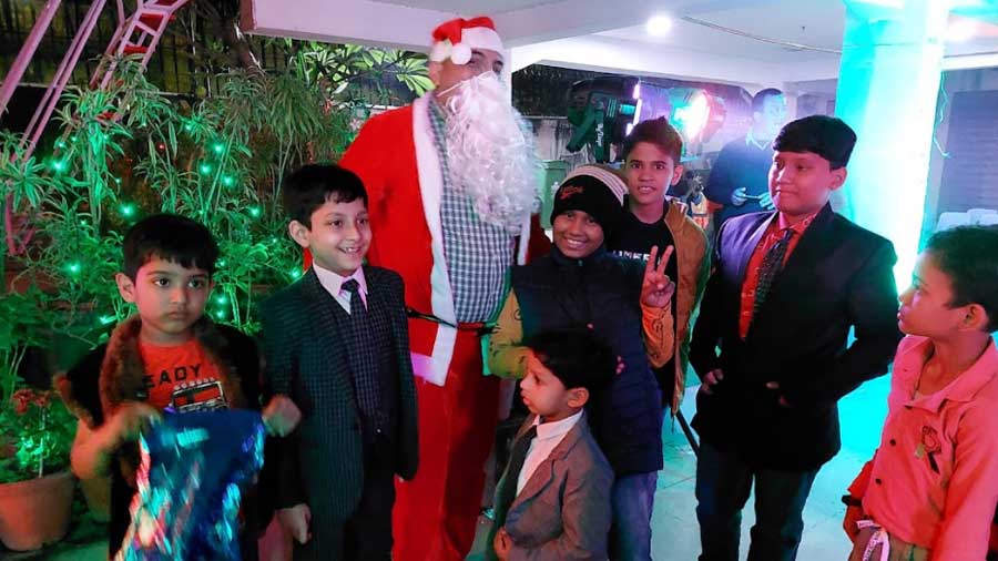 Kids crowd around and take photos with Santa, at a Kolkata celebration  