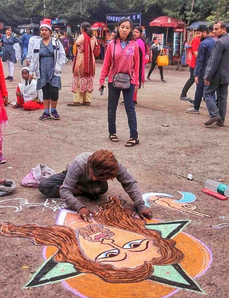 An artist gives finishing touches to a portrait of Christ on the pavement near Victoria Memorial Hall on Monday afternoon
