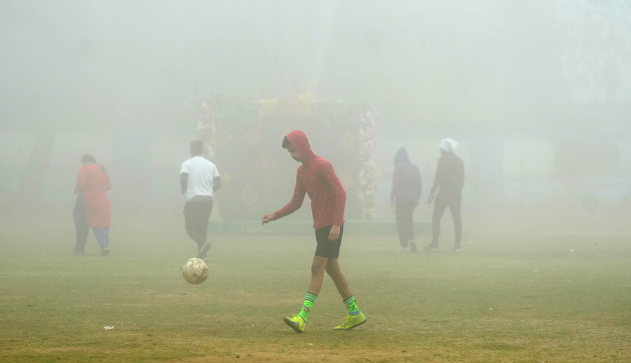 Youngsters play football amid low visibility due to dense fog in east Burdwan on Wednesday morning     
