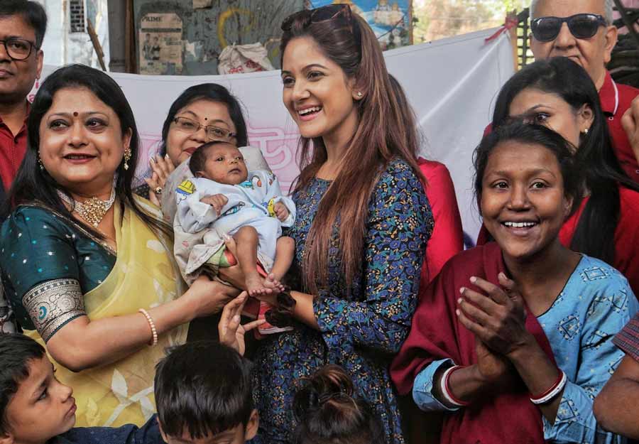 Actor Trina Saha poses with a newborn girl from Gariahat street footpath. Due to her special birth date, the child has been named Valentine. Her father, who broke his guitar, was gifted with another one so that he can support his family by busking