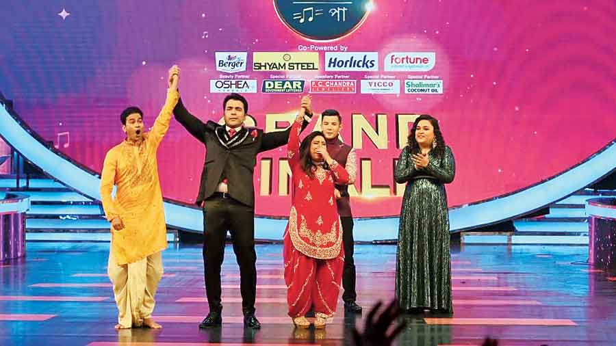 Host Abir Chatterjee holds up the hands of both Ashmita Kar (in red) and Padmapalash Haldar as joint winners of the Zee Bangla show Sa Re Ga Ma Pa at Biswa Bangla Convention Centre