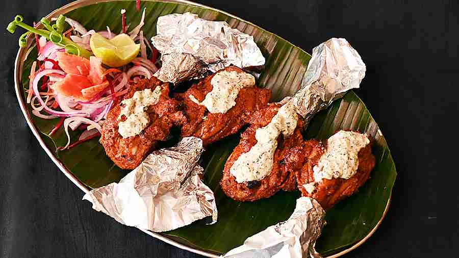 Dhania Lassoni Thecha Tangri Kebab: Marinated in quintessential Indian spices, whole pieces of chicken legs are garnished with thecha made of flour, yoghurt, and green chillies.