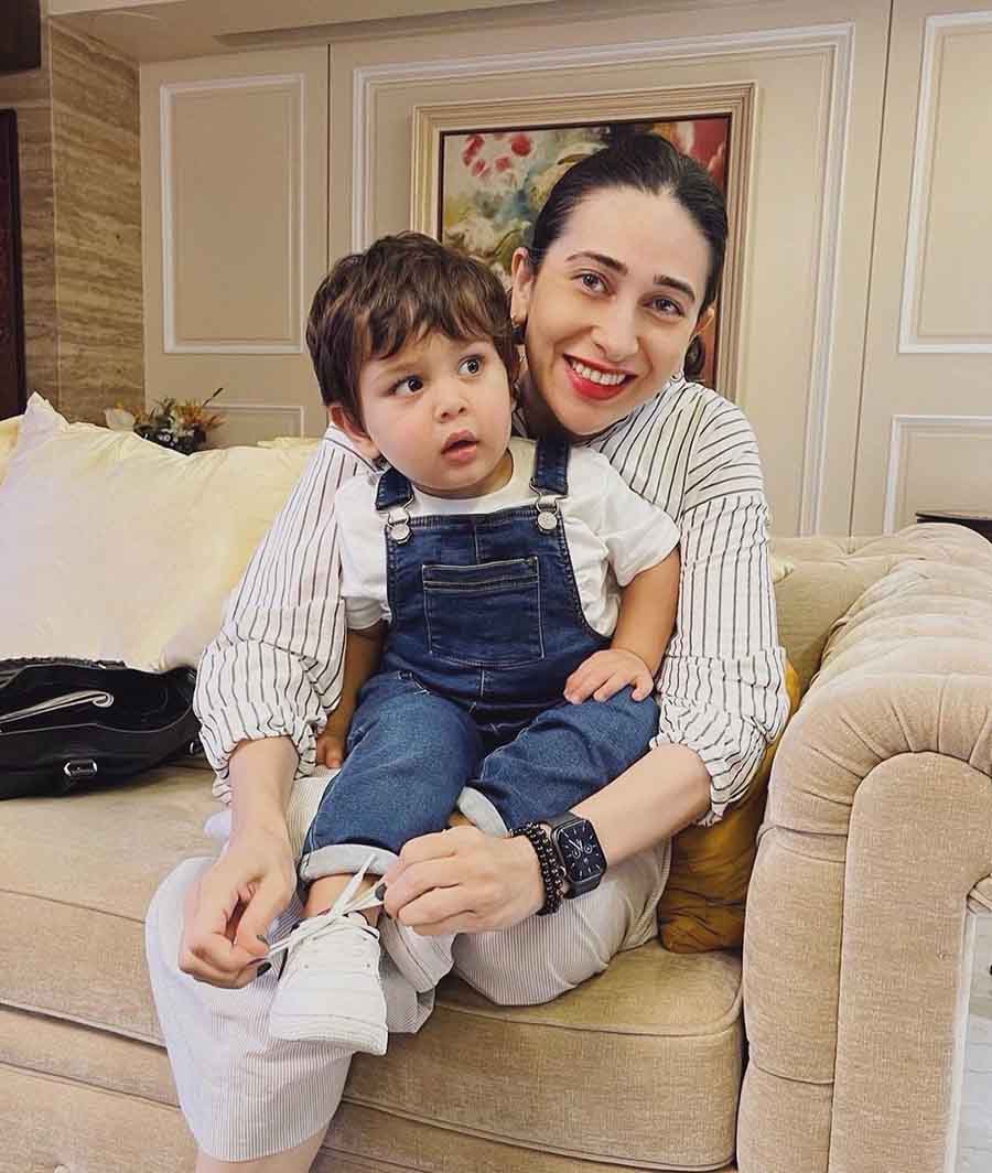 Maternal aunt Karisma shared a photo where the actress is seen tying up the shoelaces of the birthday boy. 