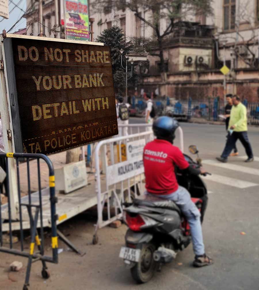 A digital road sign warns passerby of potential bank frauds and scams, alerting against the sharing of bank details