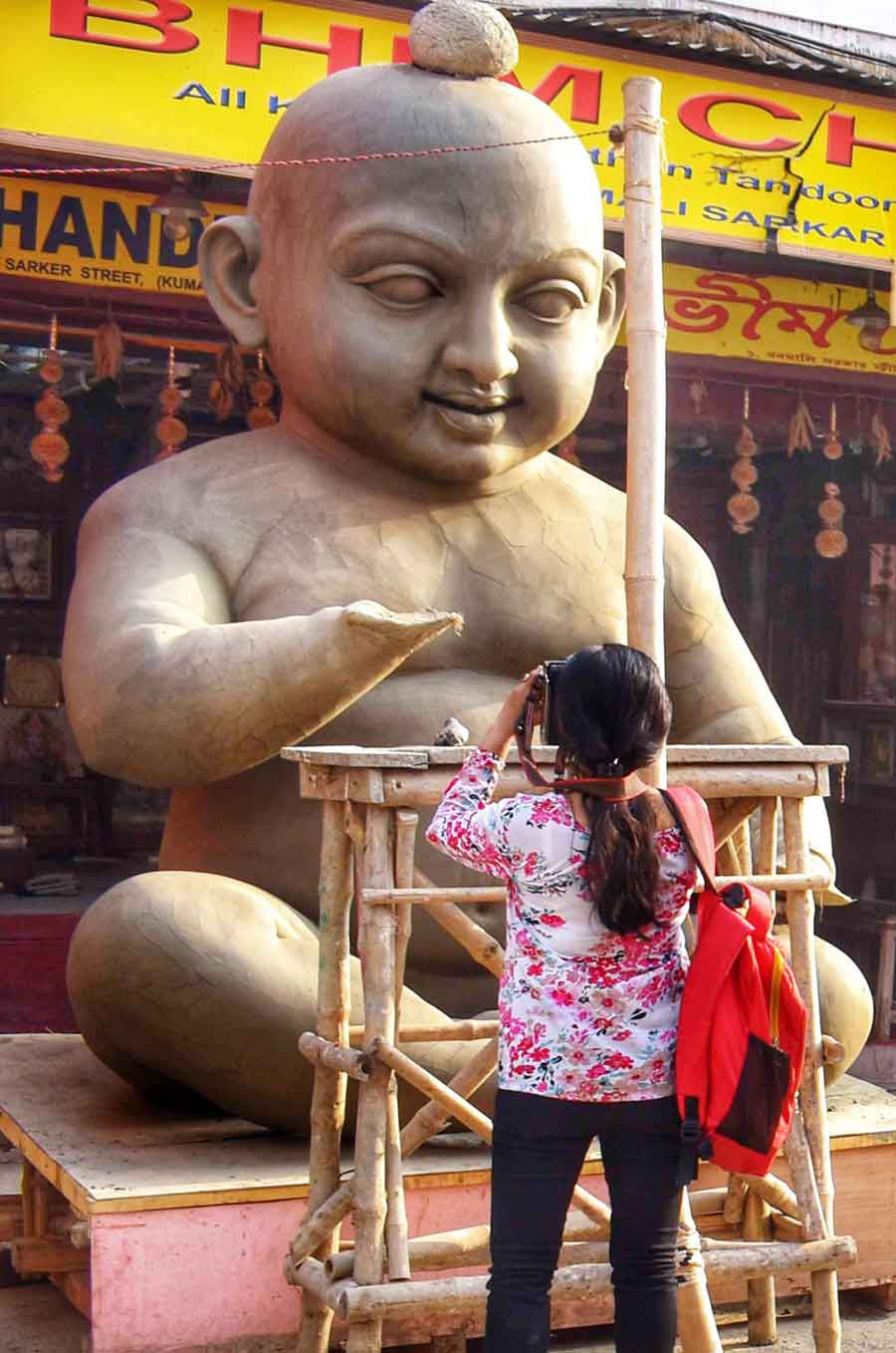  A woman takes a picture of a huge clay idol of Gopal being readied ahead of Dol Purnima