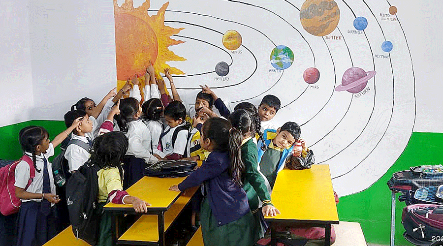Students learn about the solar system from a painting on the wall of the corporation-run school in Topsia.