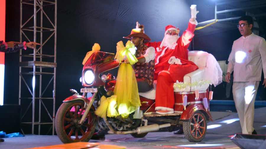 Santa Claus zoomed in on a red motor-carriage driven by an elf, much to the excitement of the kids