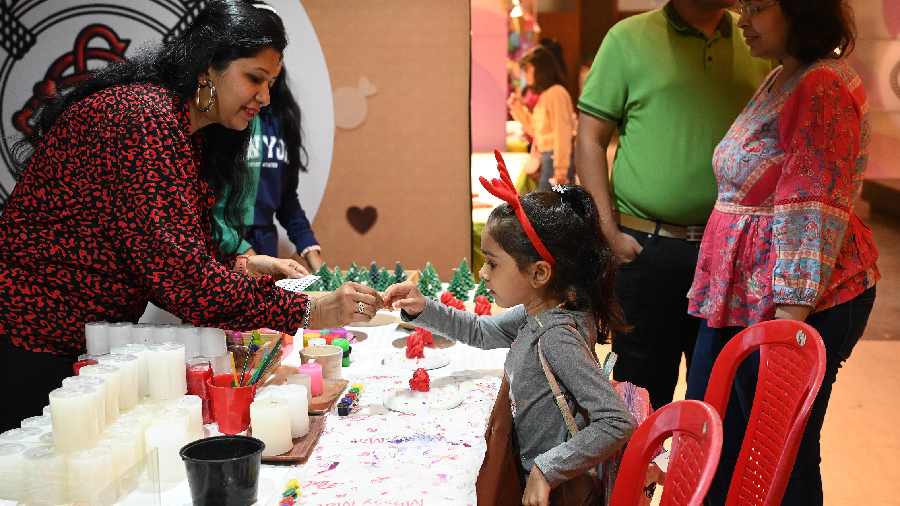 This little girl gets help painting a Christmas-themed candle, which she later took home as a gift