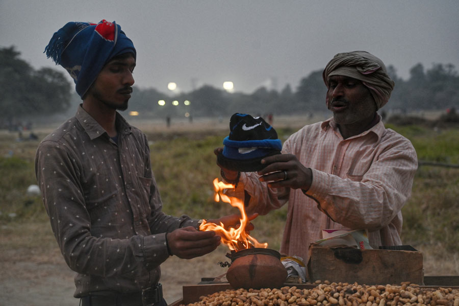 Peanut-sellers warm their hands on Thursday's chilly afternoon at the Maidan. The city continues to experience cold weather 