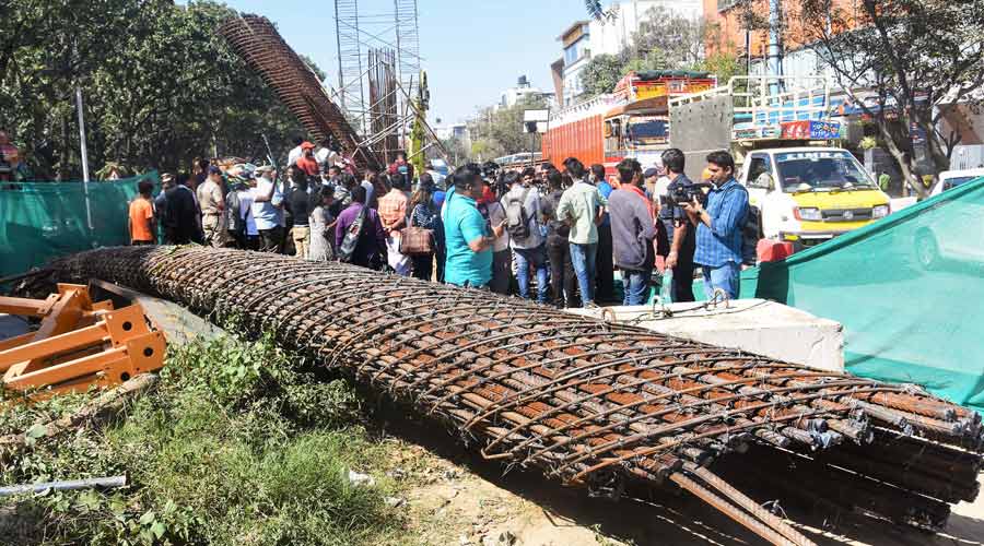 People gather at the accident site where a half broken iron structure of a metro pillar fell, at Hennur Main Road in Bangalore.