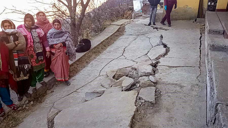 Locals stand next to a crack on the ground at Joshimath town