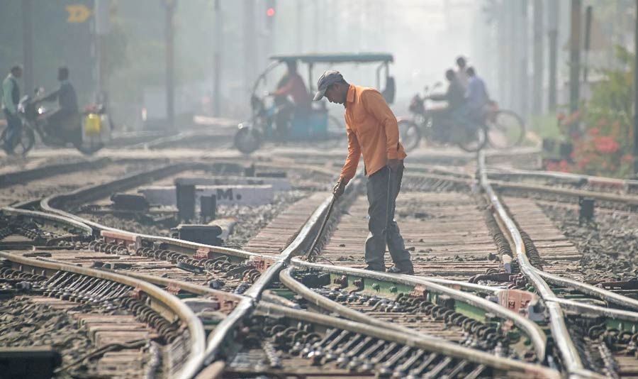 A worker checks railway tracks amid low visibility due to dense fog on a cold winter morning in Nadia on Tuesday