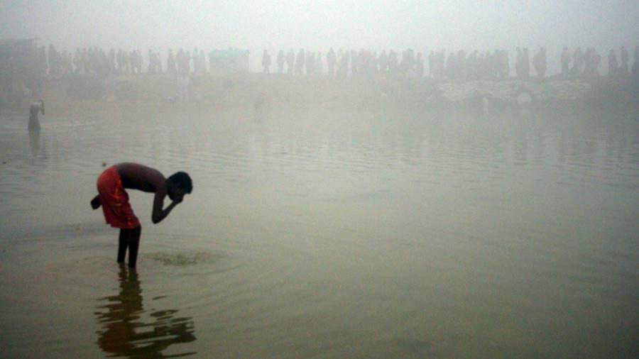 Silhouettes of several devotees walking besides Ajay River 