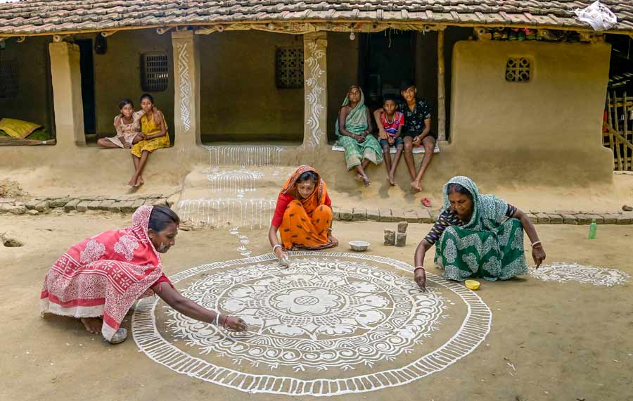 Women create a 'rangoli' in front of their house ahead of 'Makar Sankranti' in Nadia, Friday  