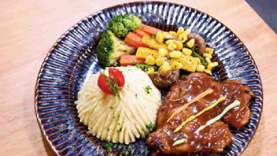 Roast Chicken in a gravy is served with mashed potatoes and stir-fried assorted veggies like broccoli, American corn, mushrooms, carrots and bell peppers.