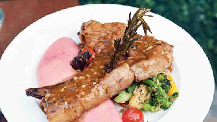 Apple cinnamon braised Pork Chops served with roasted root vegetables and creamy potato mash in red wine, garnished with burnt thyme leaves, which enhance the flavor of the dish.