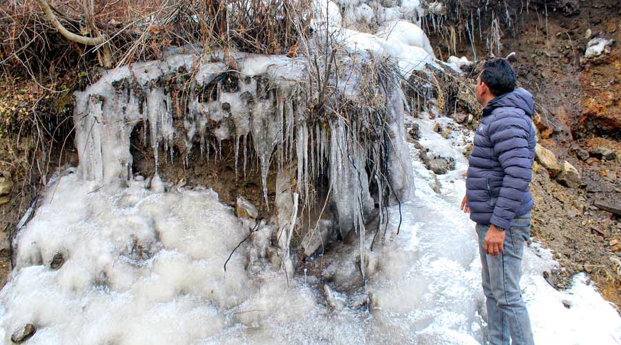 A man looks at frozen water in Subhai village of Joshimath in Chamoli district.