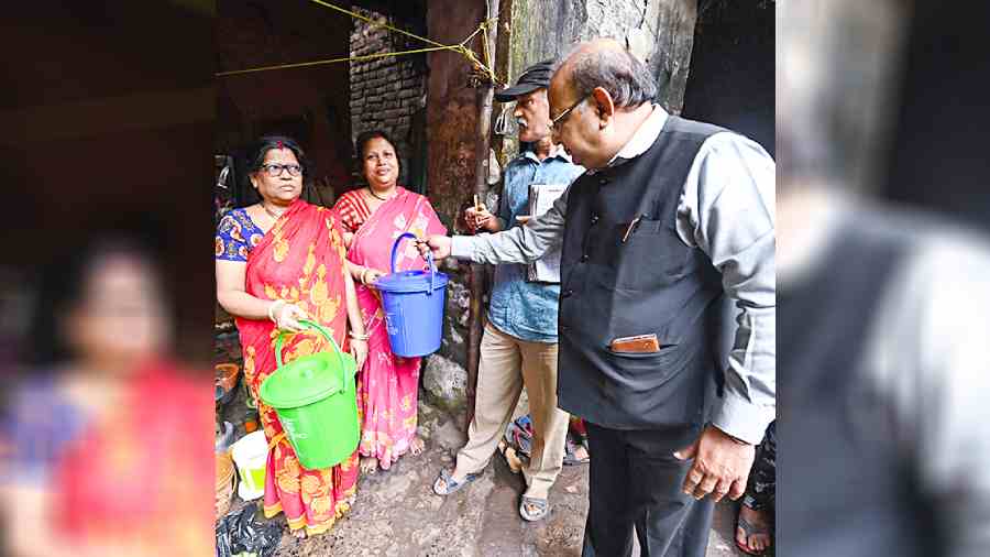 Prabir Mukherjee, councillor of Ward 83, hands waste bins to residents on Kalighat Temple Road on Sunday. 