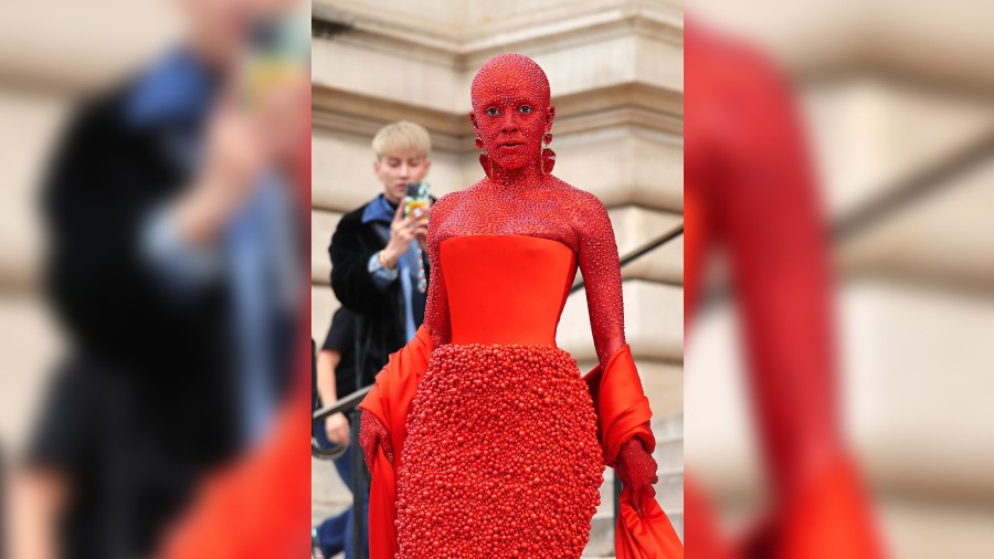 Singer Doja Cat shocked everyone when she turned up at the fashion event wearing head to toe red body paint, a red gown and 30,000 Swarovski crystals for Schiaparelli fashion show. It took her 5 hours to get ready for the event.  The avant-garde outfit is designed by  Daniel Roseberry. 