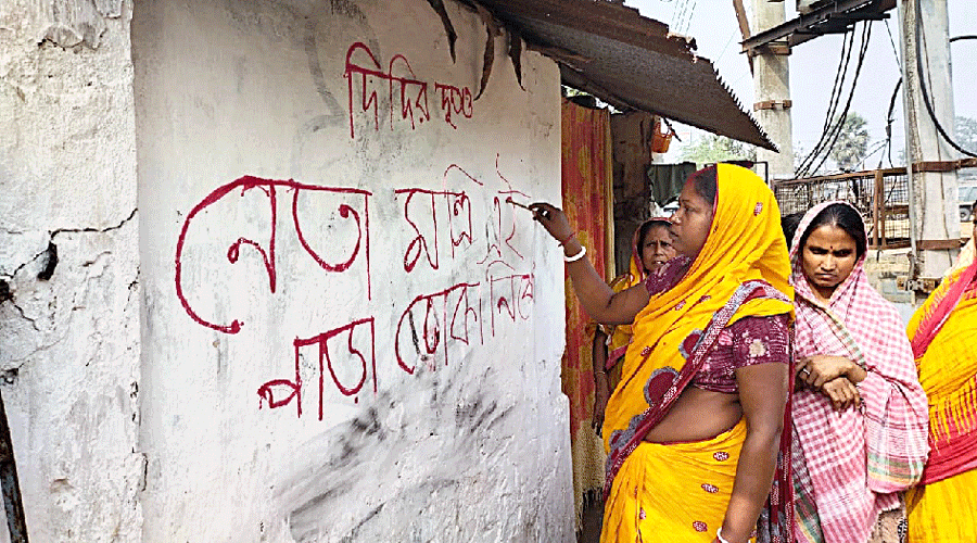 A woman writes graffiti on a wall at Pasipara village in Old Malda block on Monday, saying political leaders, ministers and ‘Didir Doots’ are barred from entering their area.