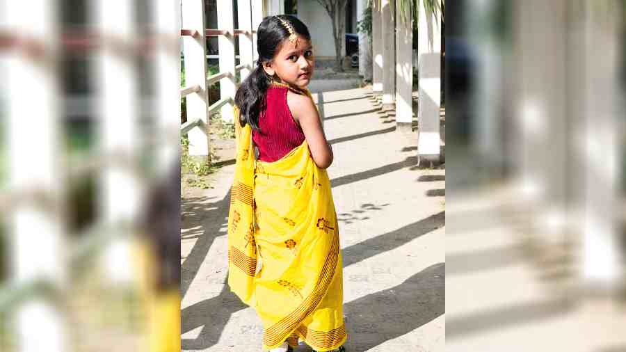 Matching the hue of the festival, a yellow sari with flower motifs in red
