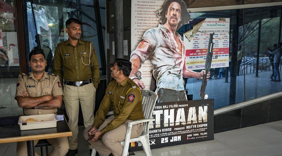 Police personnel guard at a theatre during the first day first show of Bollywood movie Pathaan