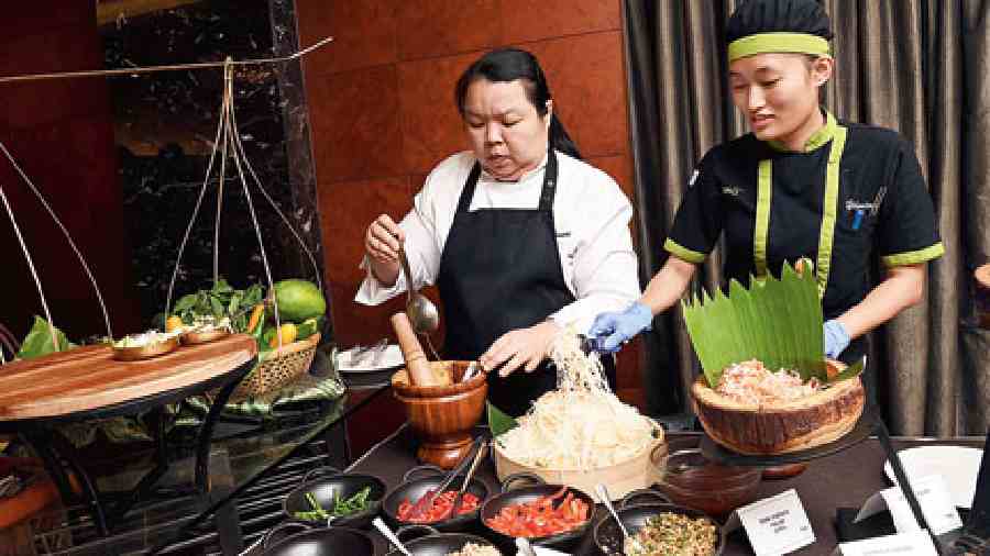 Chef Arnda Tiansiri (left) from the consul general’s staff, prepares Pad Thai Chicken