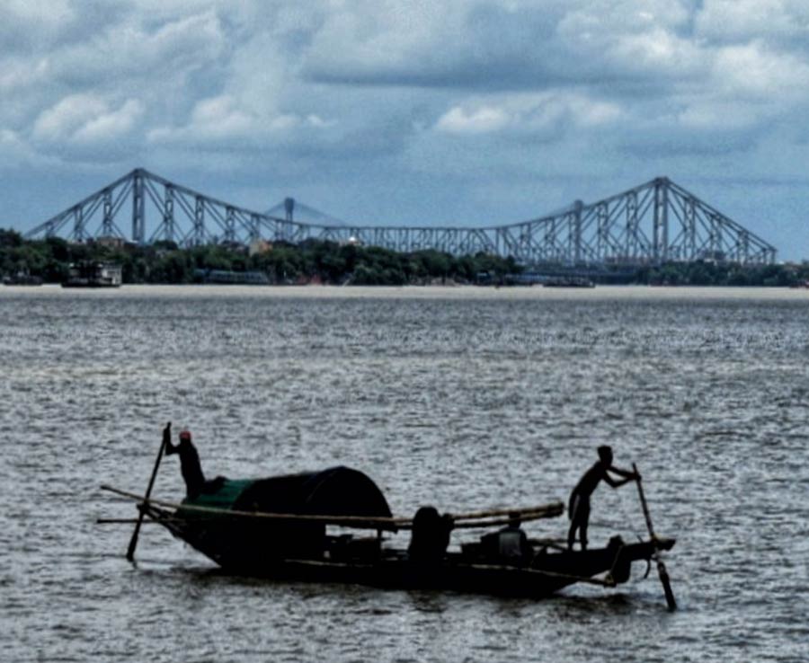 A fishing boat ventured out in the rain to catch fish from the Hooghly river   