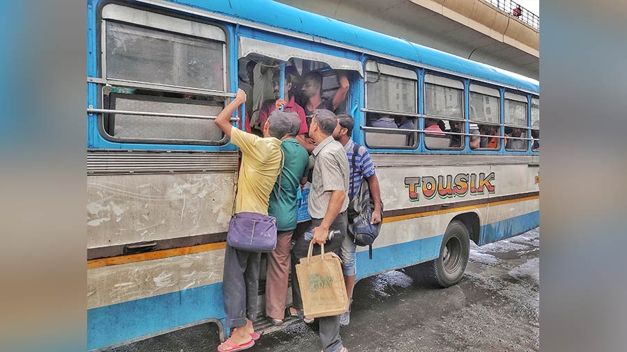 Passengers perilously hang from the footboard of a bus on the EM Bypass on Friday. Most buses have been requisitioned for poll duty leaving people stranded on roads