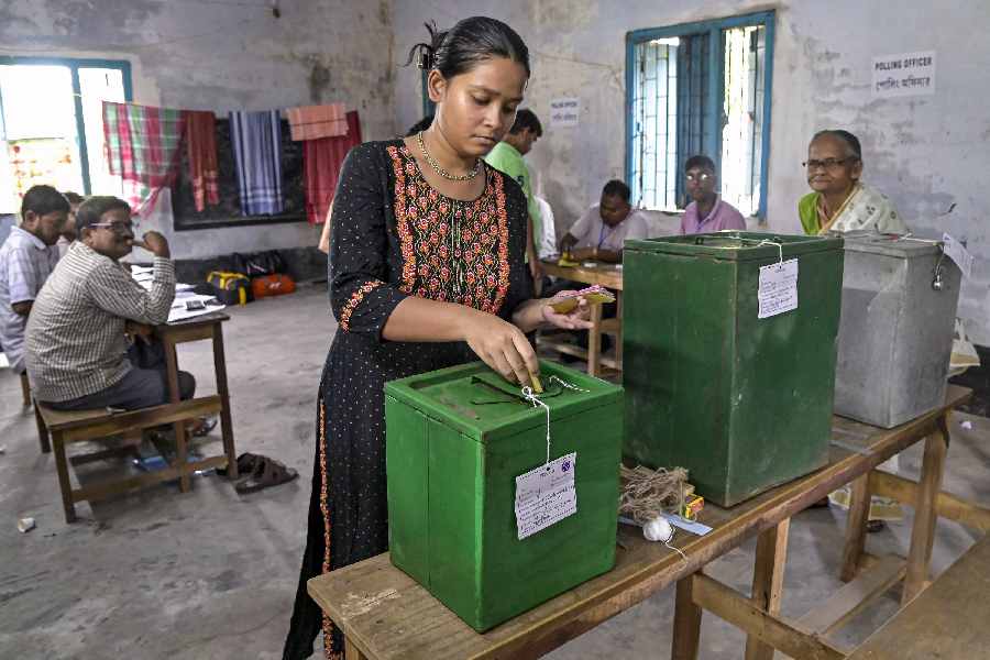 A woman drops a ballot paper while casting her vote for the panchayat elections, in Nadia.