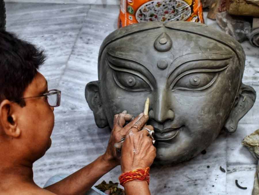 Artist Sanatan Paul adds finishing touches to a Durga idol’s face at Kumartuli 101 days ahead of Durga Puja 