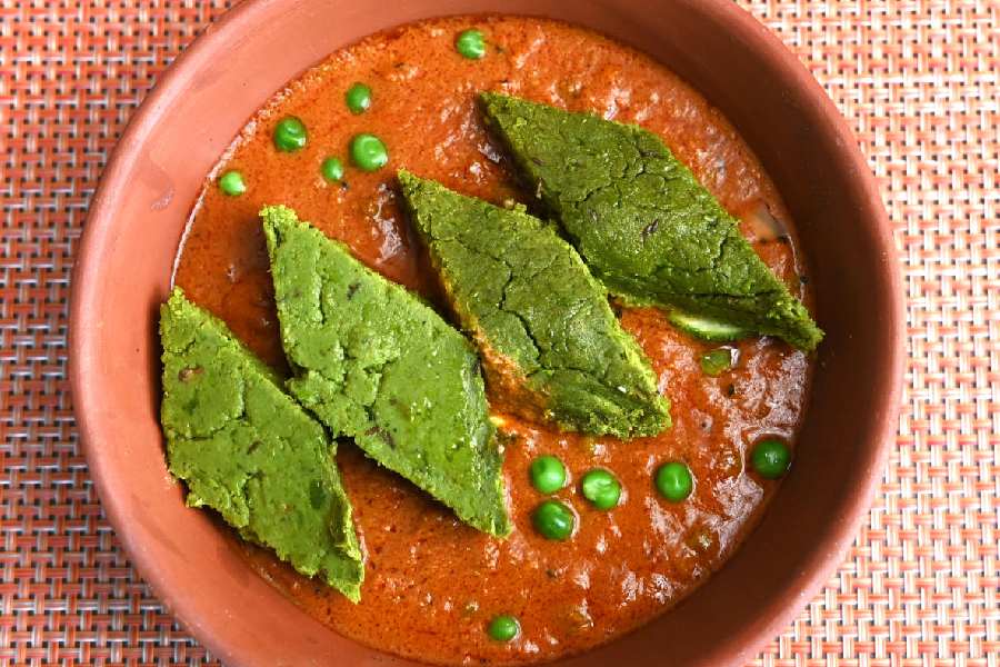 Koraishutir Dhokar Dalna are soft diamond-shaped cakes made from Bengal gram and green peas and soaked in a smooth spicy tomato gravy