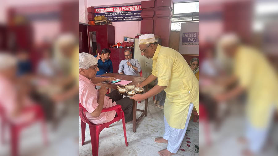 Mudar Patherya serving kheer in his skullcap and kurta