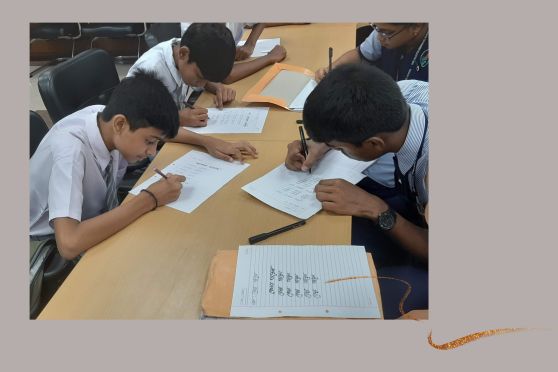 Students practice writing their names in Bengali