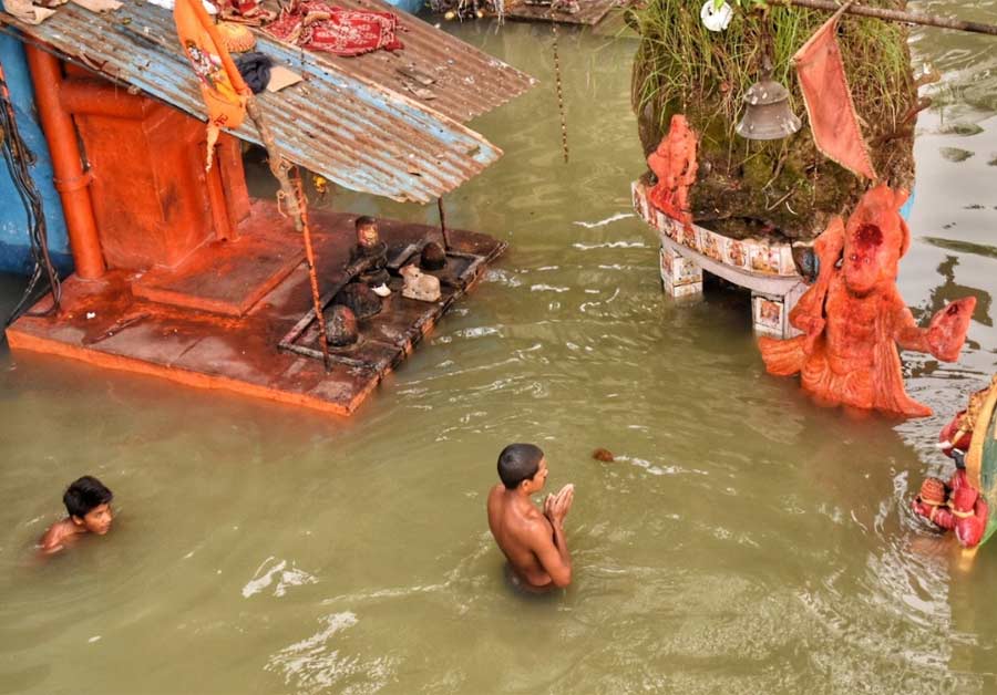 A devotee worships in front of a temple near Babughat which is inundated by high tide on Wednesday  