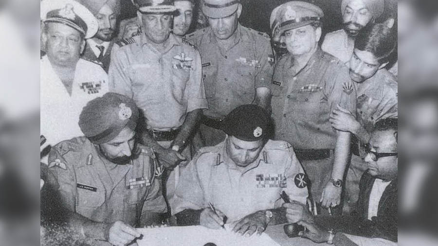 AAK Niazi signing the instrument of surrender with JFR Jacob (standing, second from right) looking on 