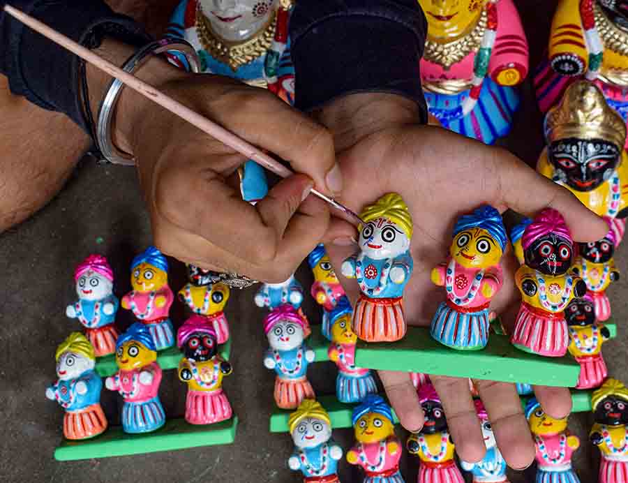 An artist paints clay idols of Lord Jagannath in Nadia on Tuesday ahead of the Rath Yatra festival