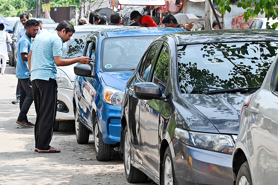 Parking attendants collect money from vehicles parked on the road leading to the passport office, behind Ruby hospital, on Tuesday.