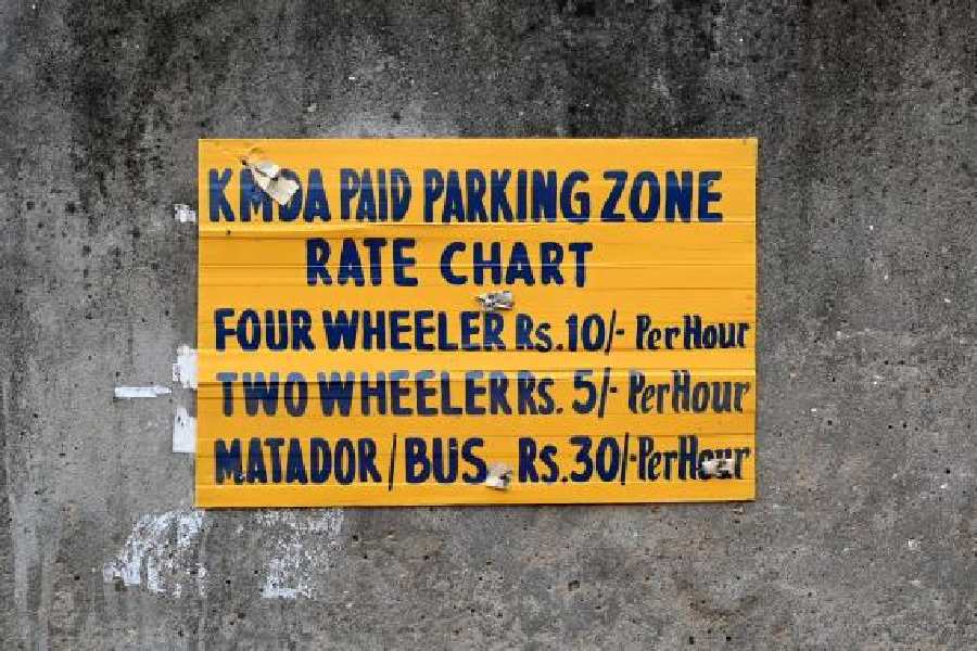 A board displays the legal parking rates along the road leading to the passport office on Wednesday; (right) cars parked on the road.