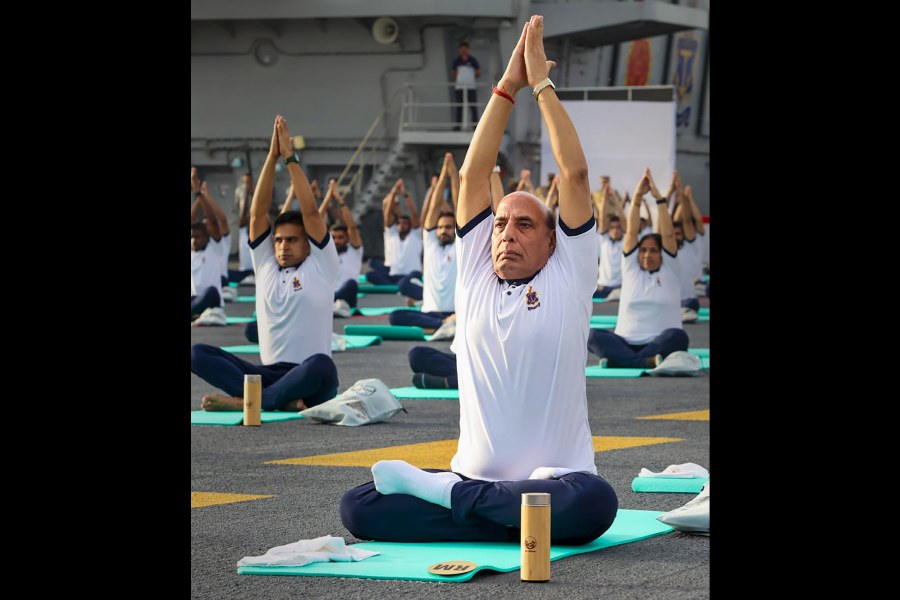 Defence Minister Rajnath Singh with others performs yoga on the International Day of Yoga onboard INS Vikrant, in Kochi. 