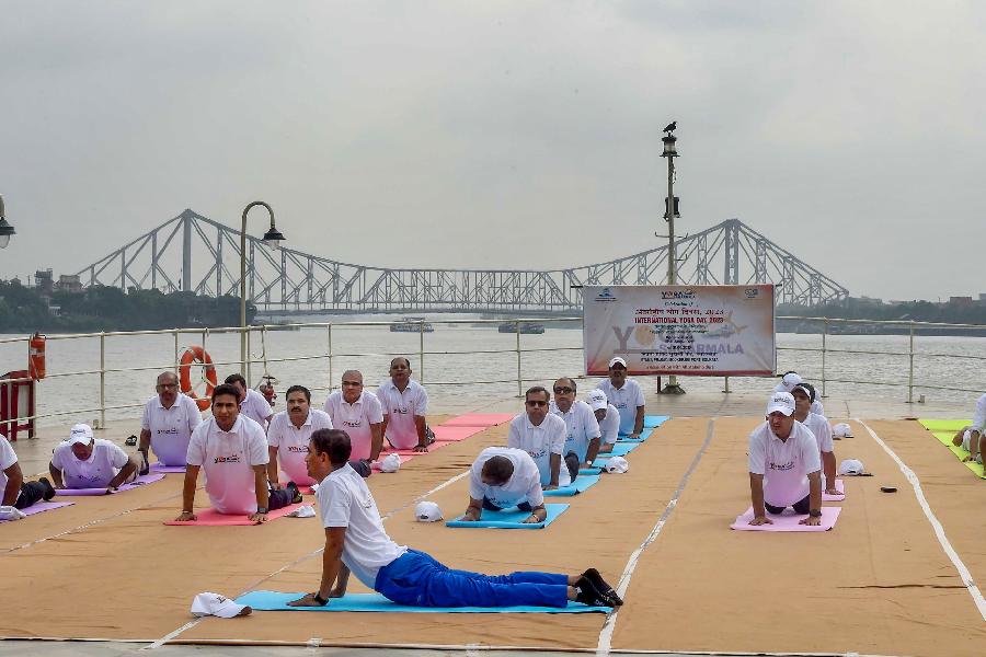 People perform yoga on the International Day of Yoga onboard paddle steamer PS Bhopal in Calcutta. 